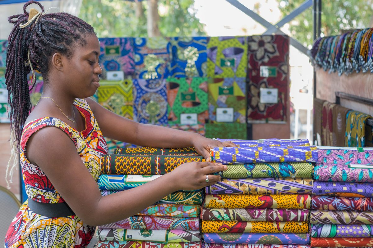 A woman arranging colourful printed fabrics at her stall